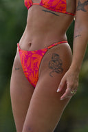 Woman in a colorful bikini standing outdoors with a blurred natural background